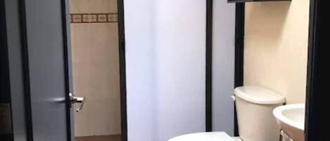 Un baño pequeño con inodoro, lavamanos y un cubo de basura.