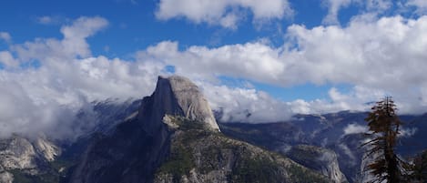 Un paysage de montagne avec un sommet imposant, une forêt dense et un ciel dégagé.