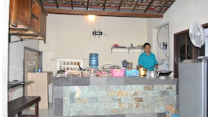 A kitchen with a stone island, wooden cabinets, and a fan. - Ganesha Home Stay (Ubud)