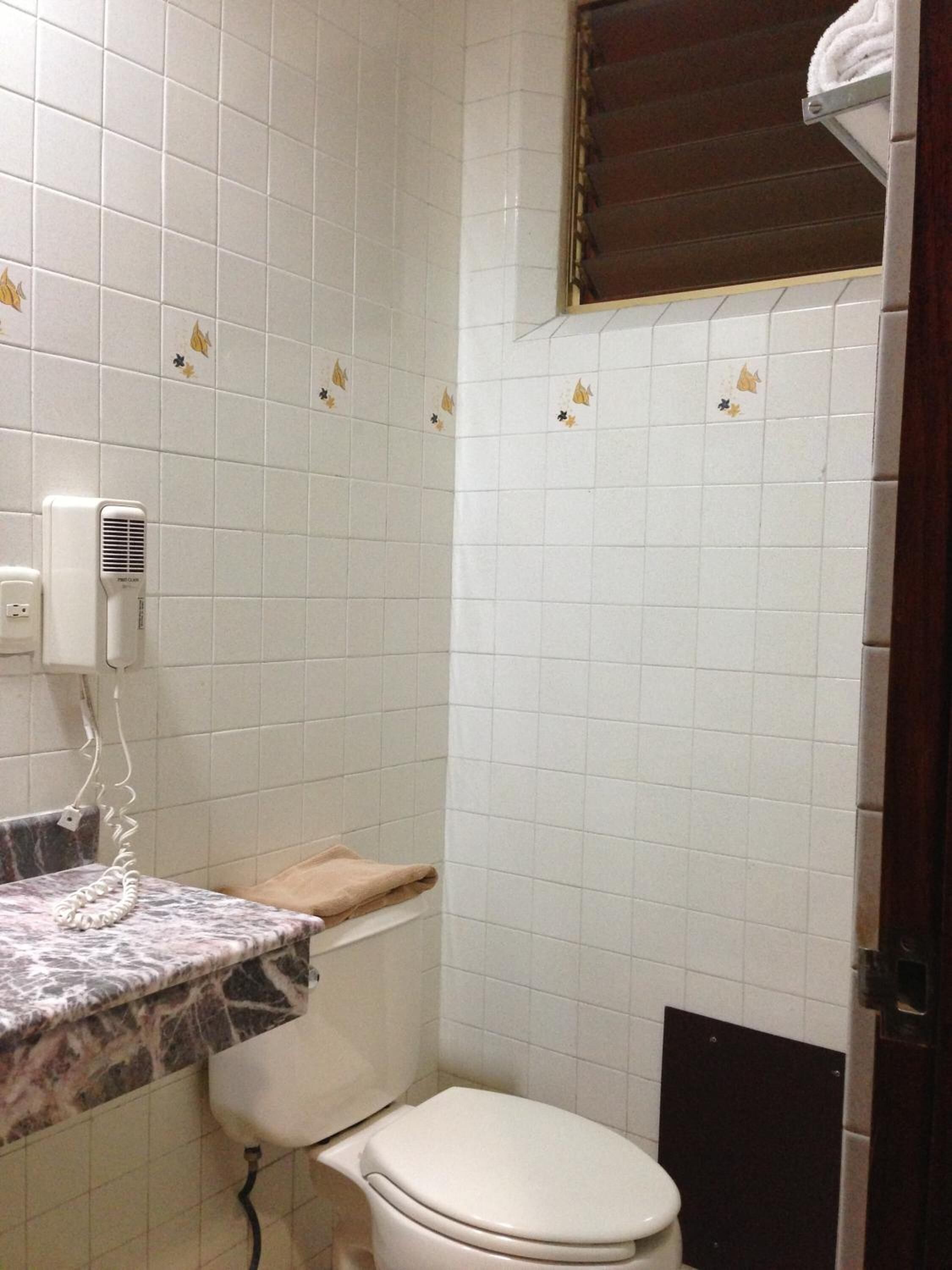 Une petite salle de bain comprenant des toilettes, un lavabo avec un plan de travail en marbre et un radiateur fixé au mur.