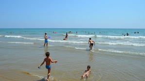 A beach scene with people swimming and playing in the water.