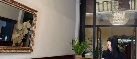 Un vestíbulo de hotel con un sofá, sillones, un espejo grande y una araña.