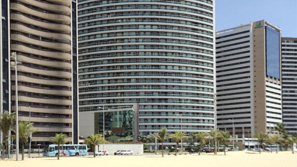 Een modern hotel met een gebogen gevel, meerdere balkons en een centrale ingang.
