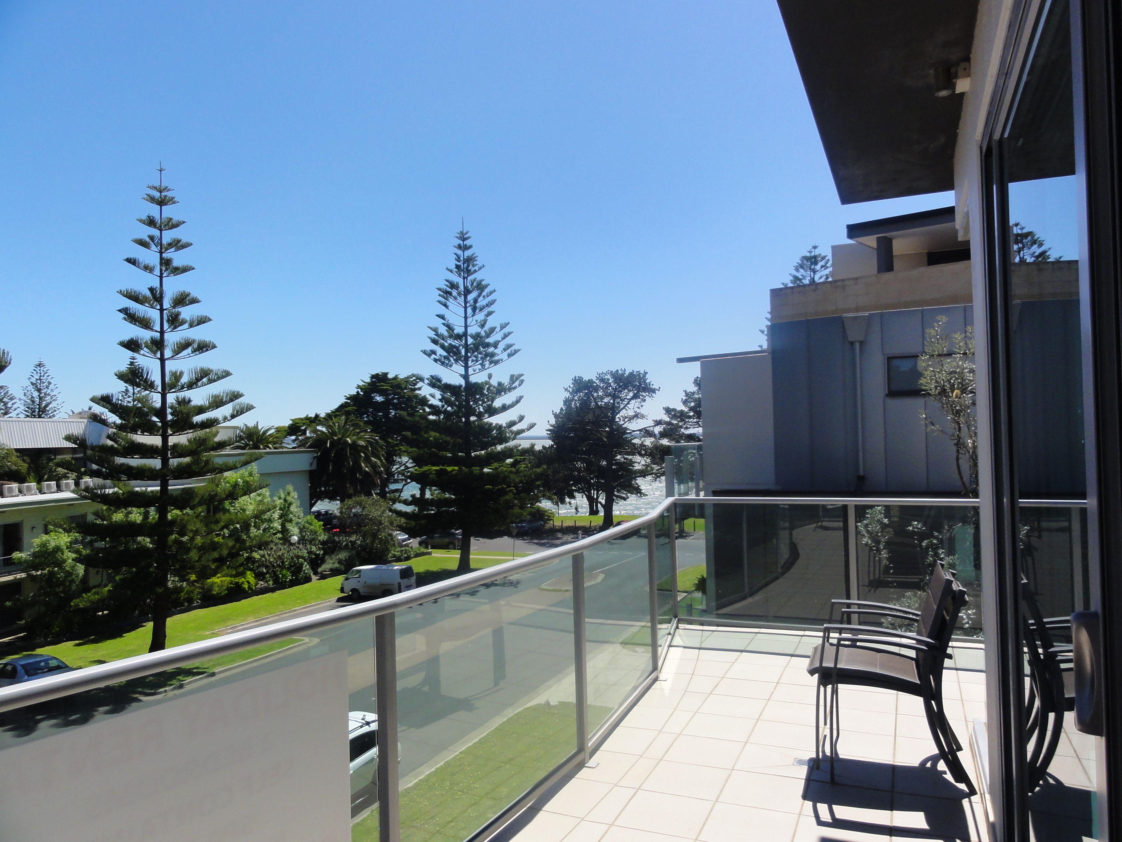 A balcony with a clear view of a road and surrounding trees.