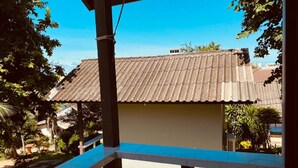 A building with a corrugated metal roof, surrounded by greenery and a clear blue sky. - Phupha Bungalow (Ko Pha-ngan)