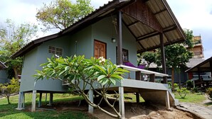 A two-story house with a sloped roof, a porch, and a small garden area. - Phupha Bungalow (Ko Pha-ngan)