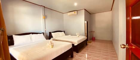 A hotel room with two beds, a red door, and a tiled floor.