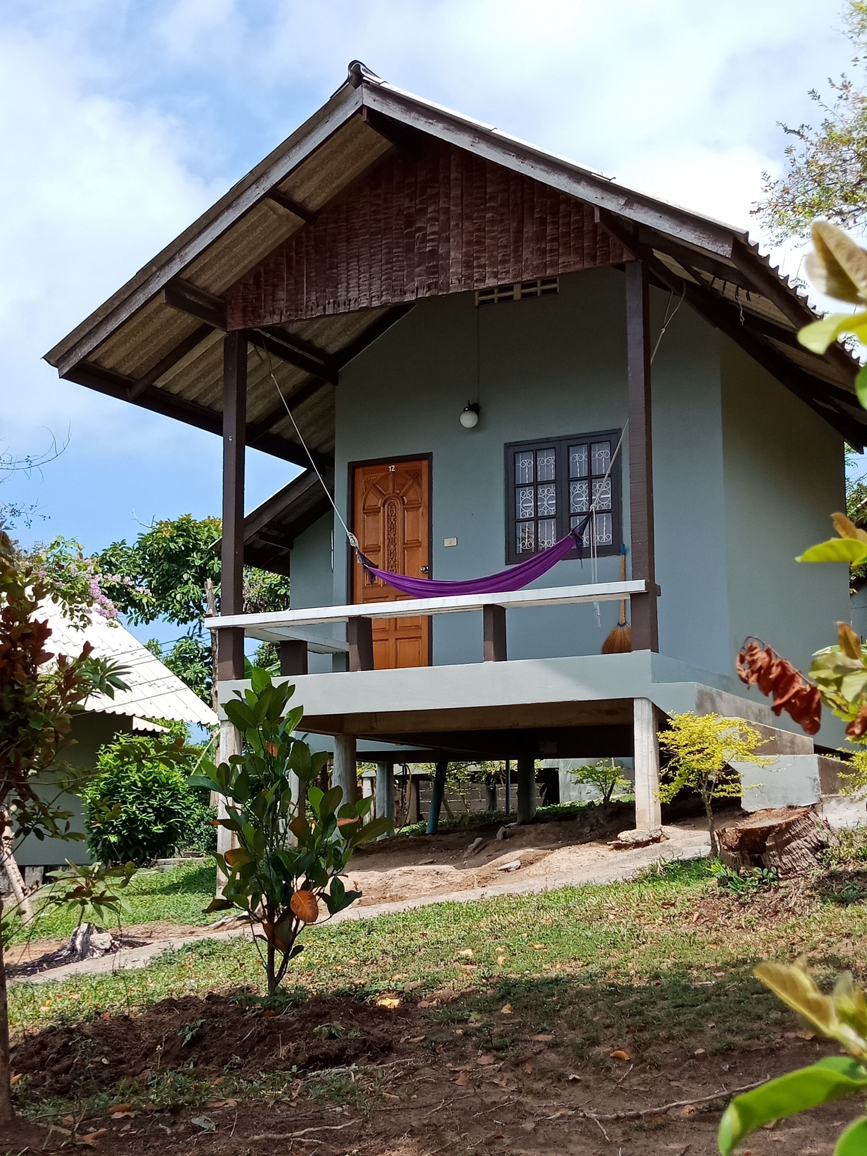 A two-story house with a balcony, a wooden door, and a window with decorative bars.