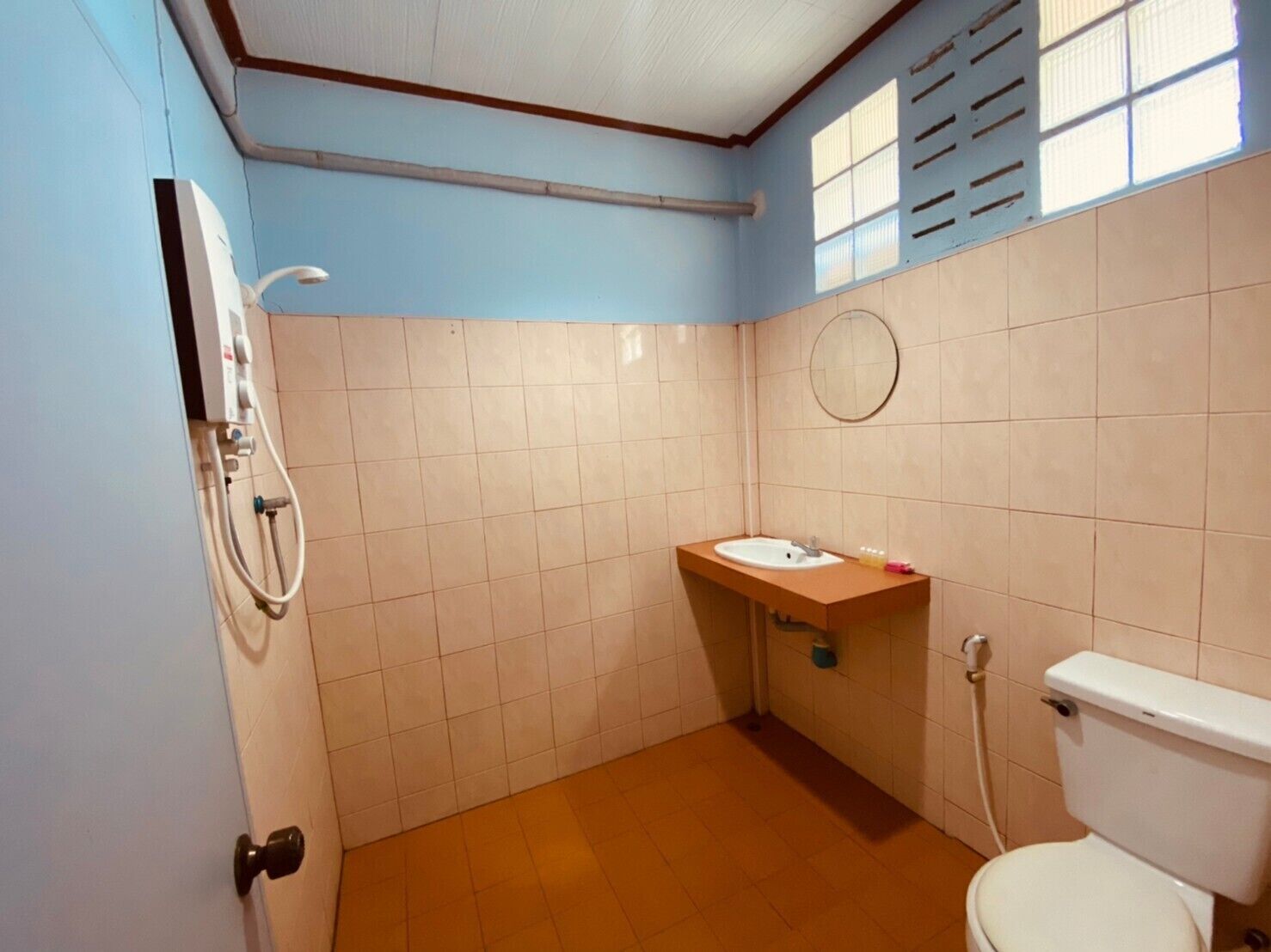 Et lille badeværelse med toilet, vask og brusebad.