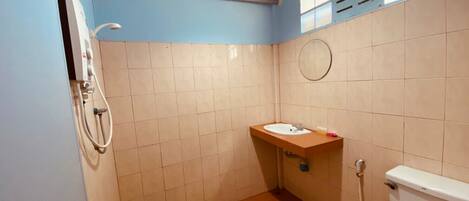 Et lille badeværelse med toilet, vask og brusebad.