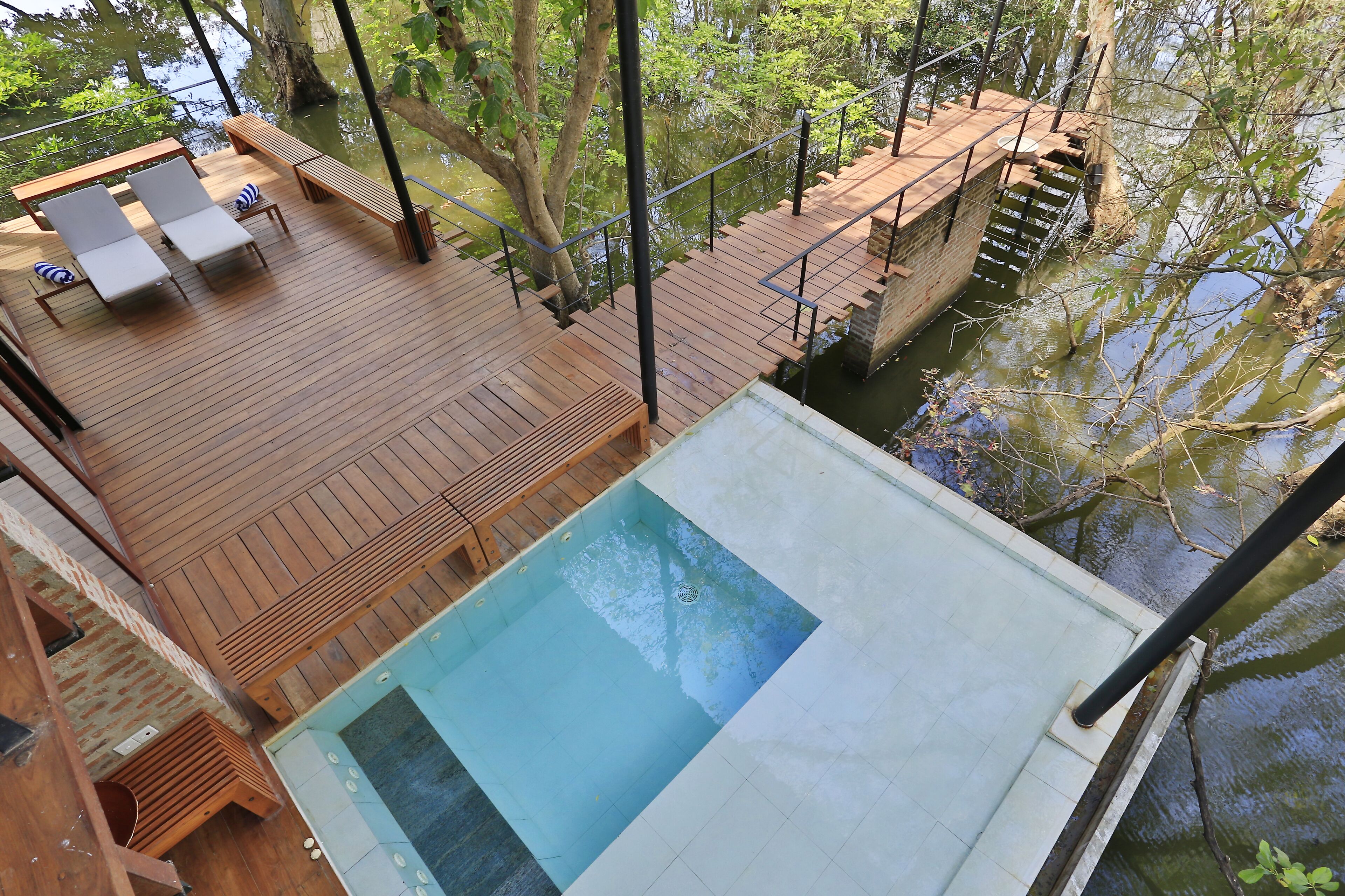 Un terrazzo in legno con poltrona relax e piscina.