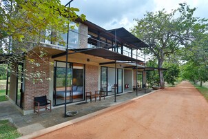 Una casa moderna con un patio, ventanas amplias y una zona de estar exterior cubierta.