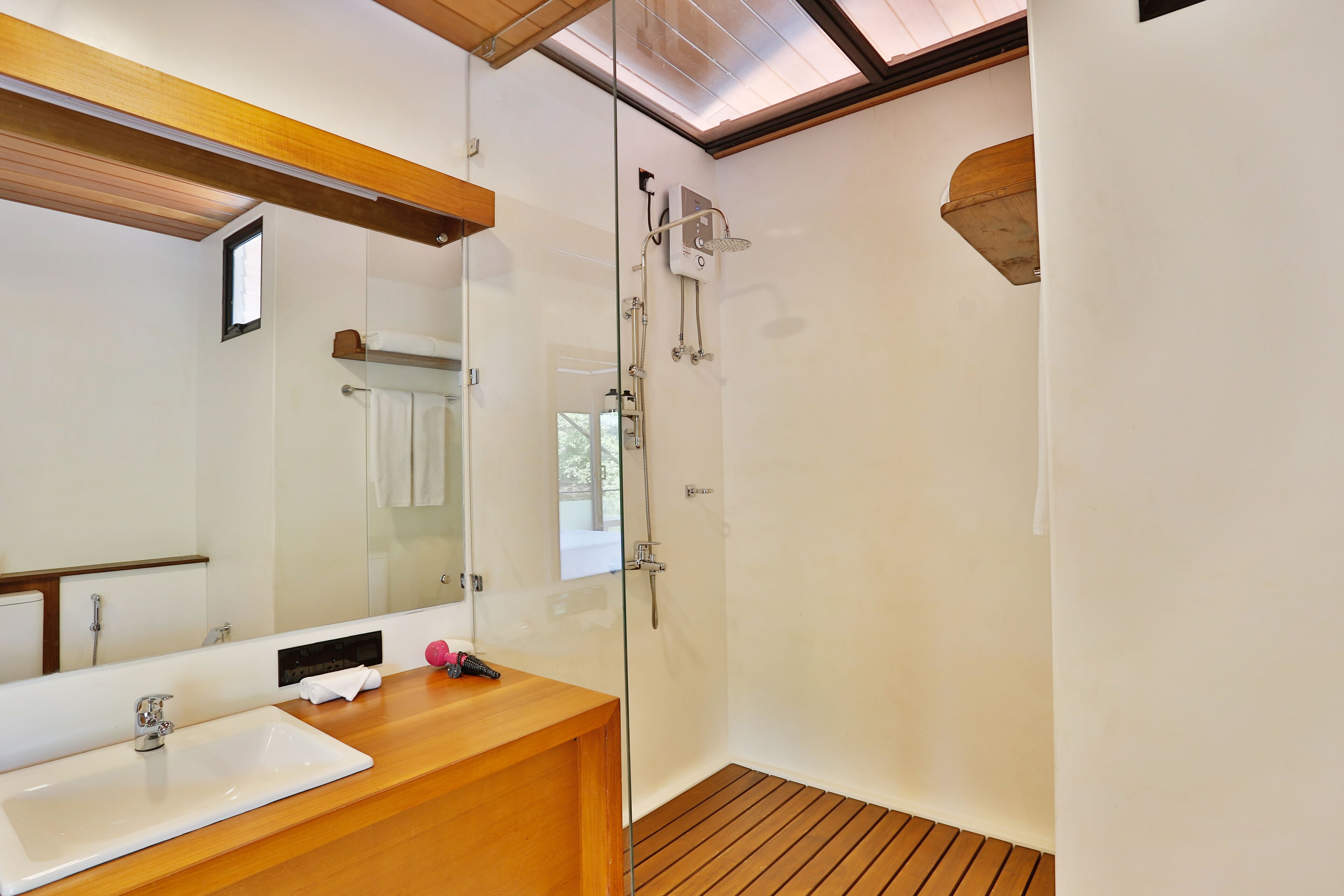 A modern bathroom with a wooden vanity, a glass shower enclosure, and a large mirror.