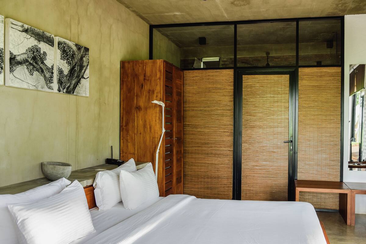 A modern bedroom with a large bed, wooden wardrobe, and a desk with a chair.