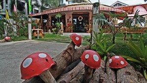 A building with a red and white facade, a front porch, and a garden with red mushroom decorations. - Gabby's Bed and Breakfast (Dumaguete)