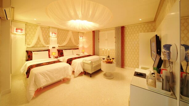 A hotel room with two beds, a vanity with a mirror, and a small table with toiletries. - Ivy Hotel (Ansan)