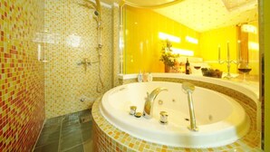A bathroom with a large bathtub, a shower area, and a mirror with a yellow wall. - Ivy Hotel (Ansan)