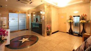A hotel reception area with a star-shaped floor design, a reception desk, and a glass door leading to the lobby. - Ivy Hotel (Ansan)