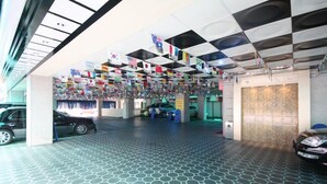 A hotel lobby with hexagonal patterned flooring, a ceiling with black and white checkered tiles, and flags hanging from the ceiling. - Ivy Hotel (Ansan)