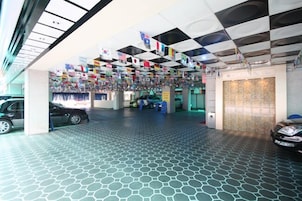 Un vestíbulo de hotel con piso de patrón hexagonal, techo de baldosas a cuadros blancos y negros, y banderas colgando del techo.