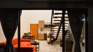 Un interior moderno con una escalera, una zona de cocina y un área de estar con un sofá rojo.