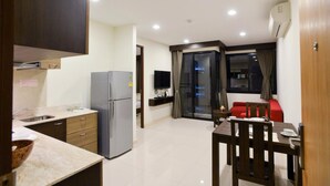 Un espacio habitable compacto con kitchenette, comedor y zona de estar con un sofá rojo.