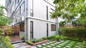 Un edificio moderno con un patio jardín, senderos de piedra y diversas plantas.