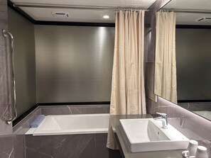 Un baño moderno con bañera, lavamanos y cortina de ducha.