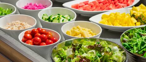 A buffet with various dishes including vegetables, fruits, and salads.