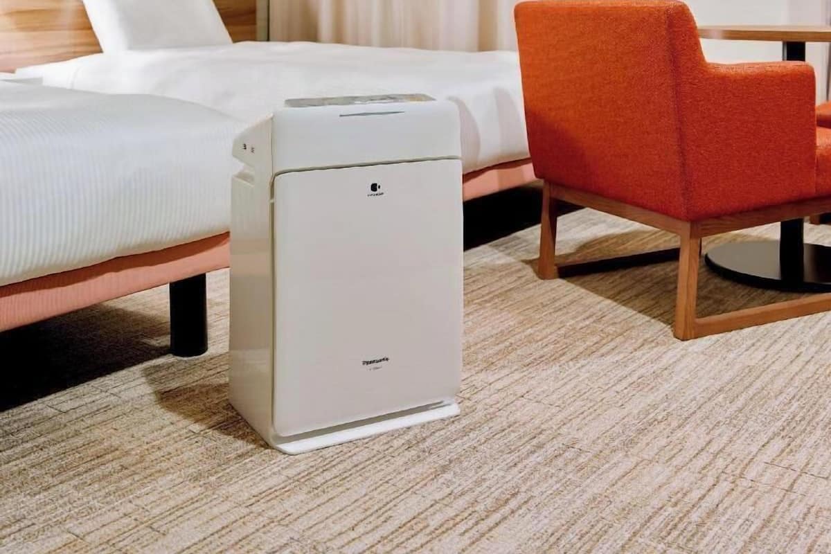 Een hotelkamer met een bed, een witte draagbare kachel en een oranje stoel.