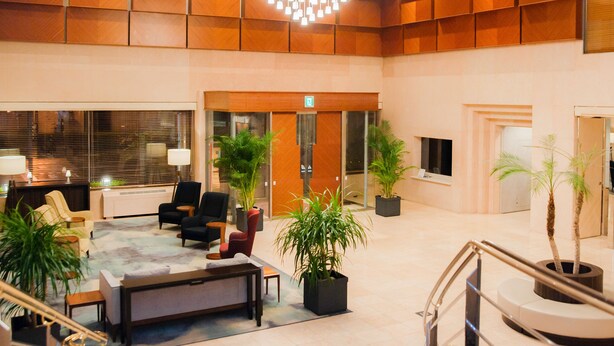 A spacious lobby with a reception desk, seating area, and potted plants.
