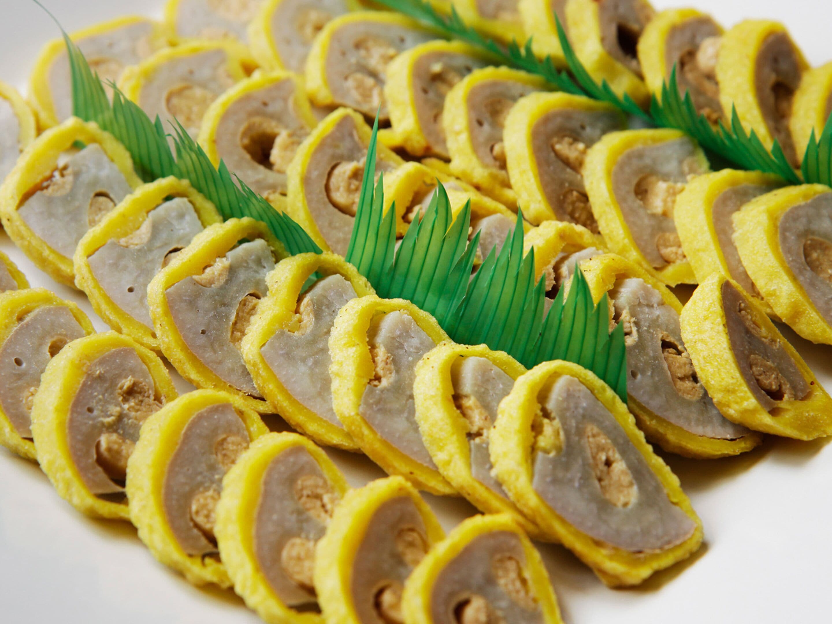 A plate of sliced food items, possibly a type of meat or seafood, arranged in a circular pattern with green leaves as garnish.