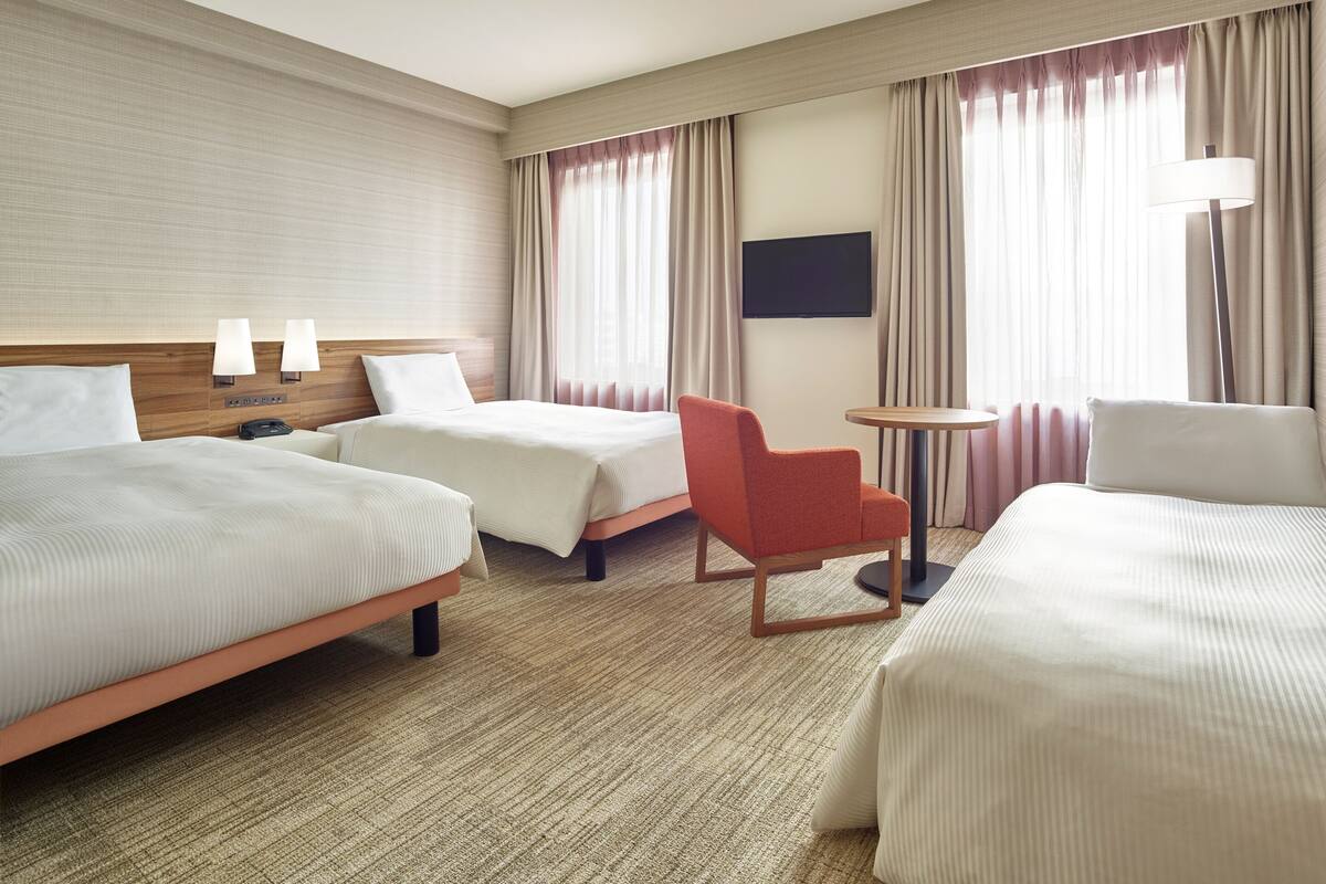 Een hotelkamer met twee bedden, een tafeltje, een stoel en een televisie.
