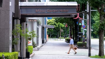 The entrance to Mitsui Garden Hotel with a covered walkway and a pedestrian crossing.