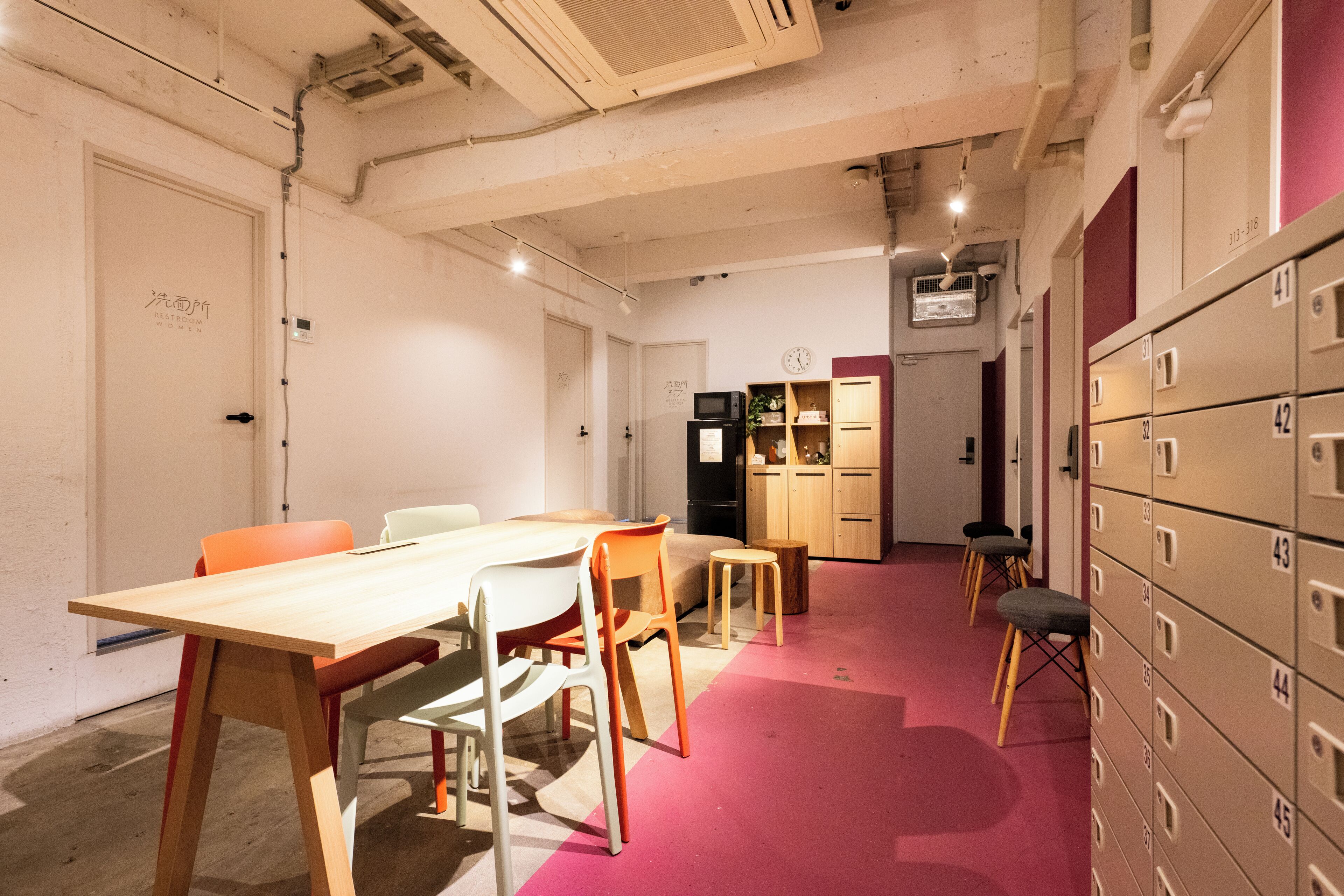 A conference room with a long table, chairs, a small sofa, and a kitchenette area with cabinets and a microwave.