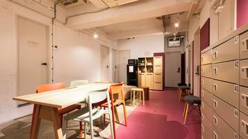 A conference room with a long table, chairs, a small sofa, and a kitchenette area with cabinets and a microwave.