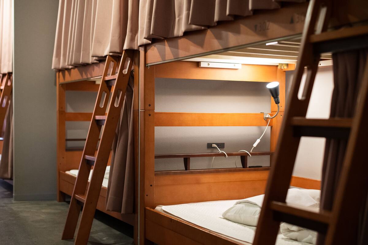 A bunk bed room with a ladder, a desk, and a lamp.