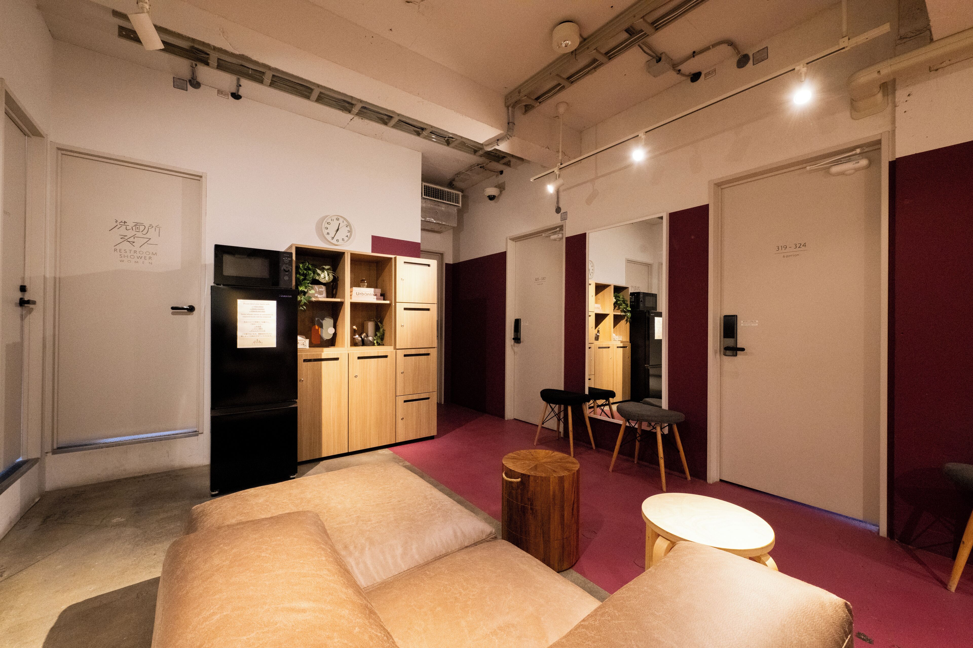 A modern interior with a sofa, wooden cabinets, a refrigerator, and a dining area.