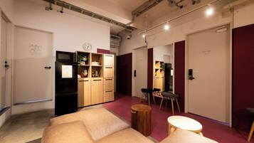 A modern interior with a sofa, wooden cabinets, a refrigerator, and a dining area.