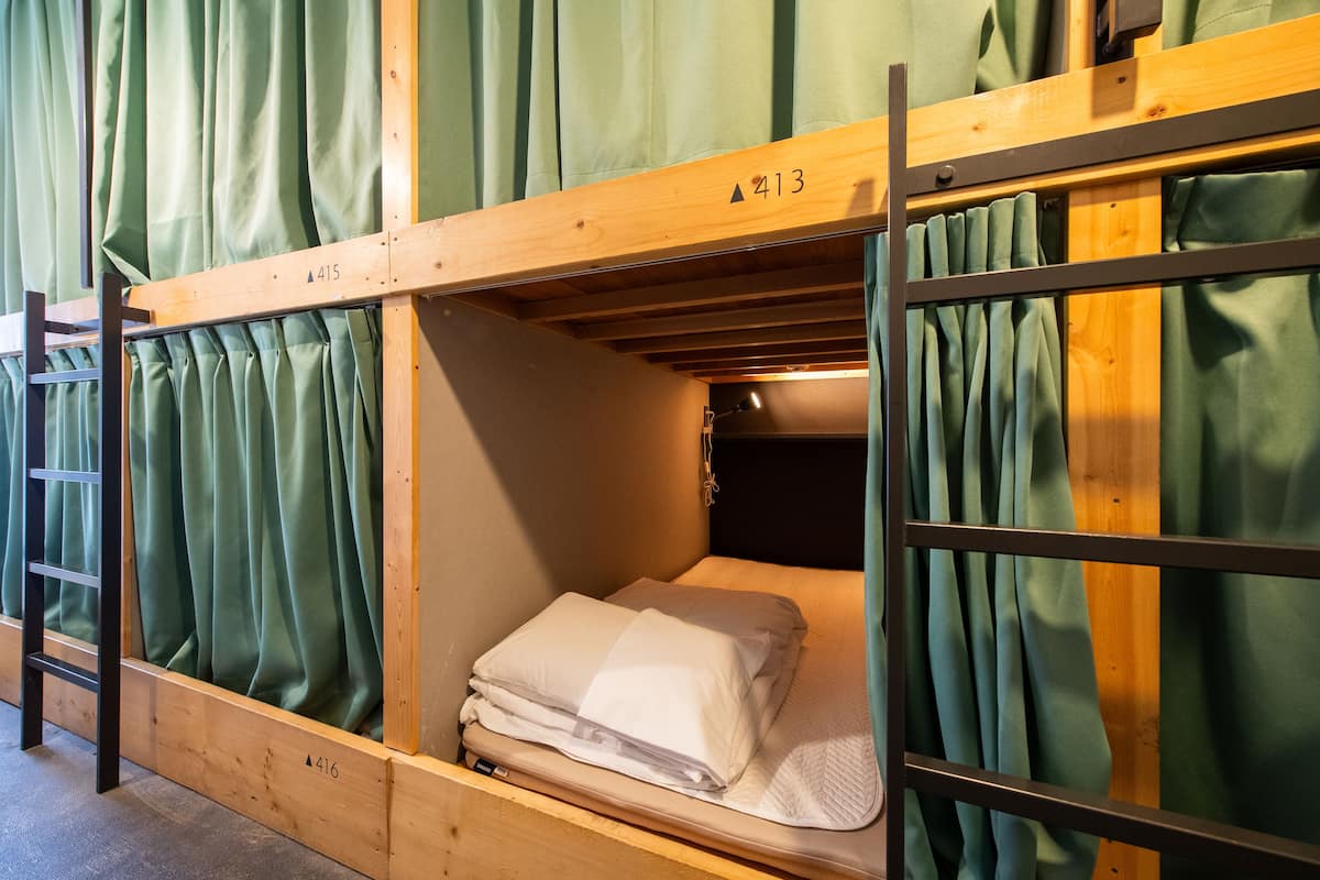 A bunk bed with a wooden frame and green curtains.