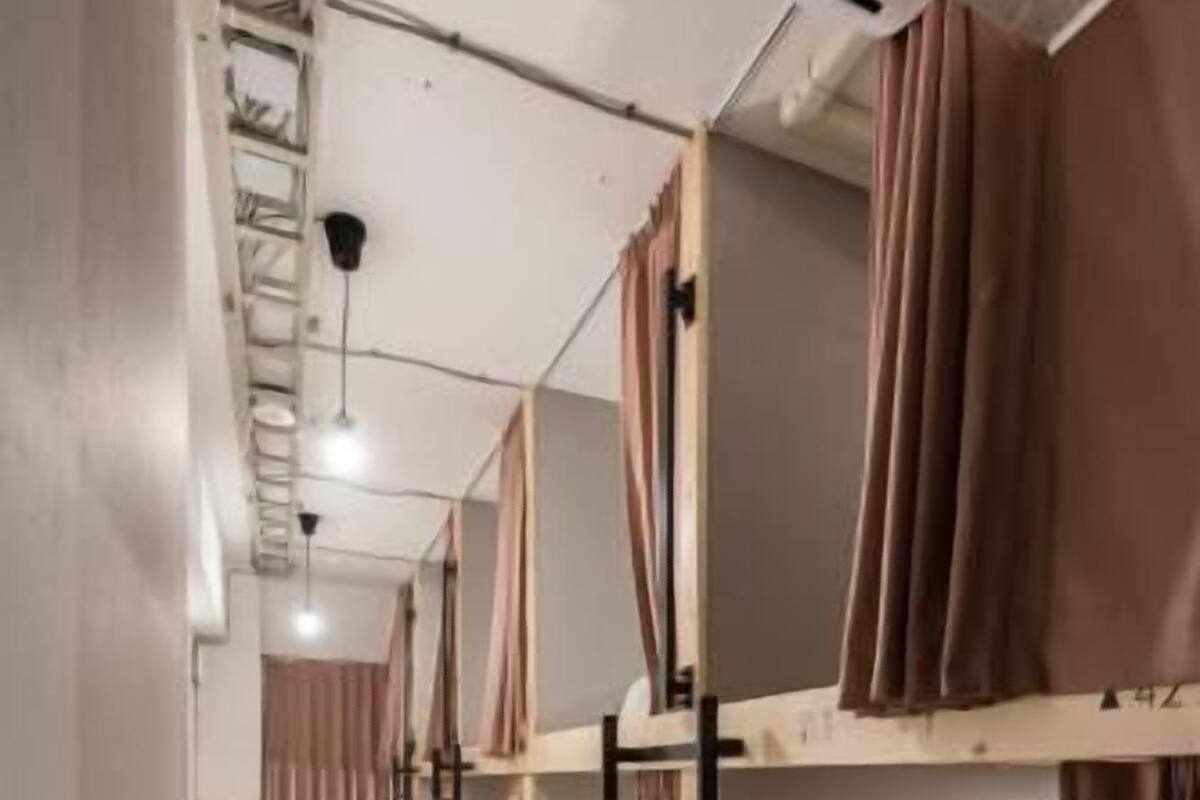 Un dormitorio con literas, barandillas de madera y cortinas.