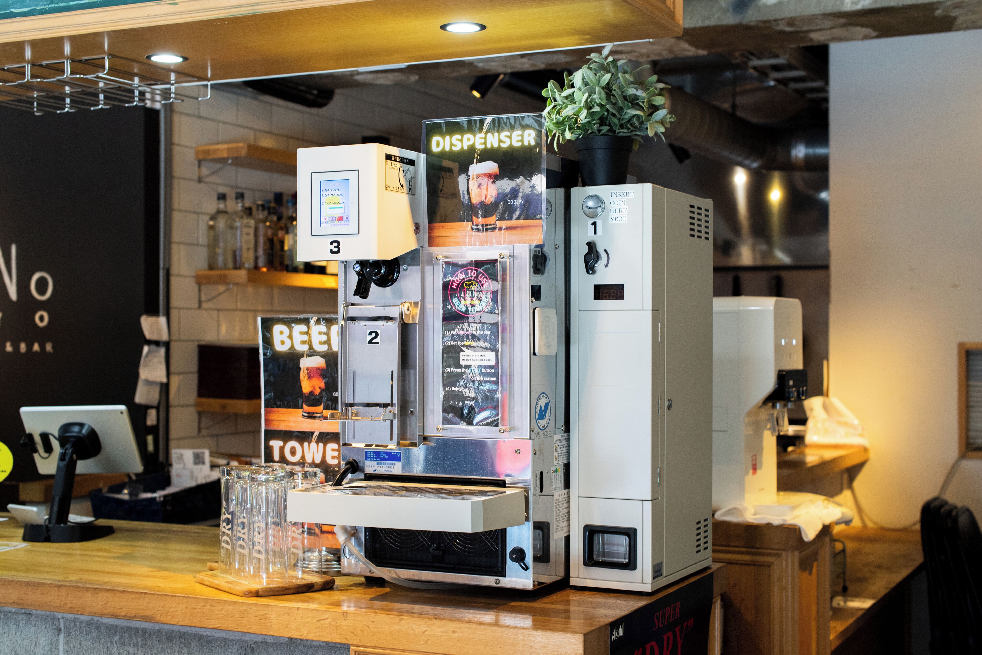 A coffee machine with a dispenser, a digital display, and a small plant on top.