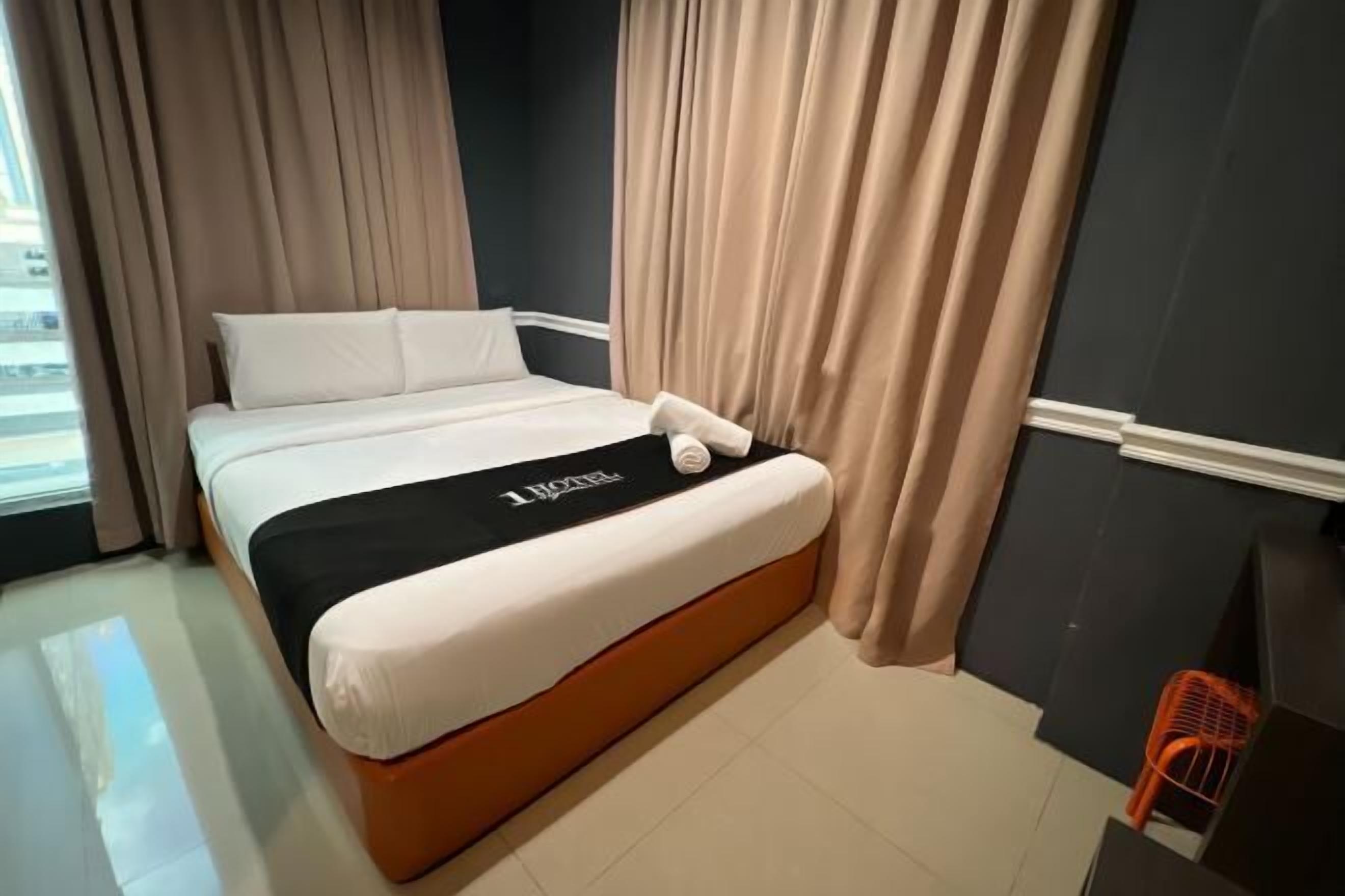 A hotel room with a bed, curtains, and a view of the city.