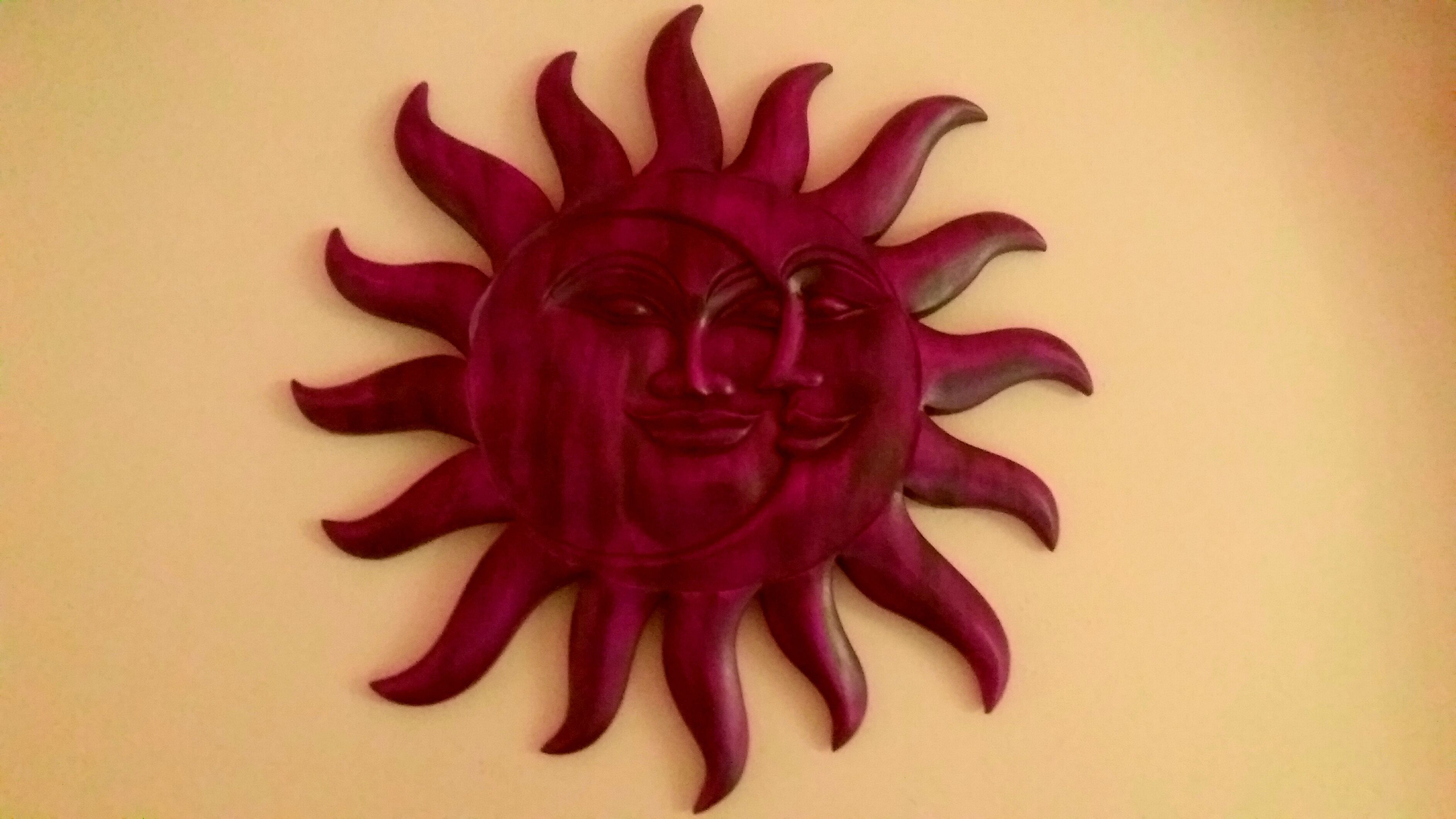 A wall decoration of a stylized sun with a face.