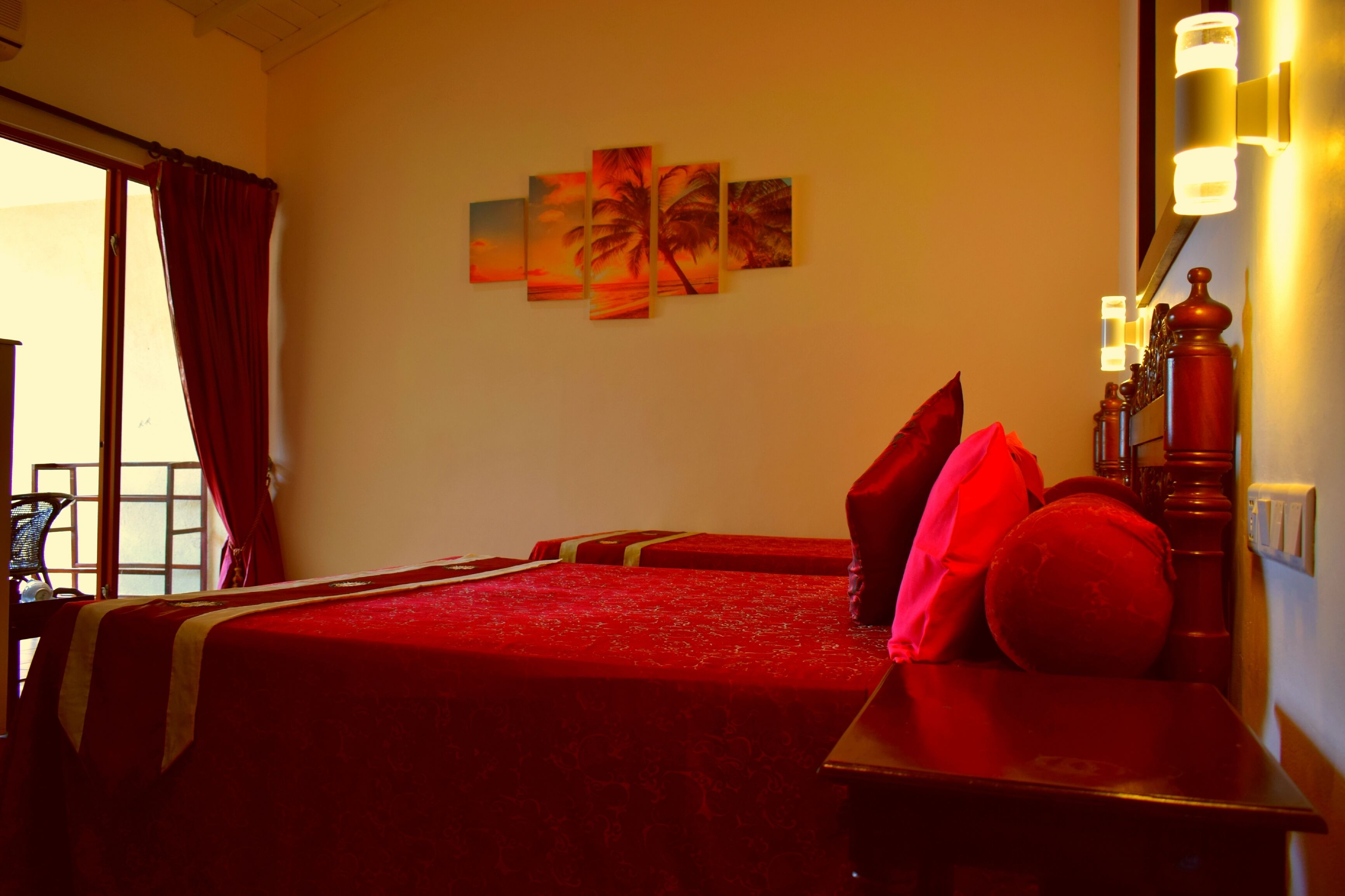 Habitació d'hotel amb un llit gran, una taula de treball i una cadira. Hi ha llums penjades a la paret i una finestra amb cortines.