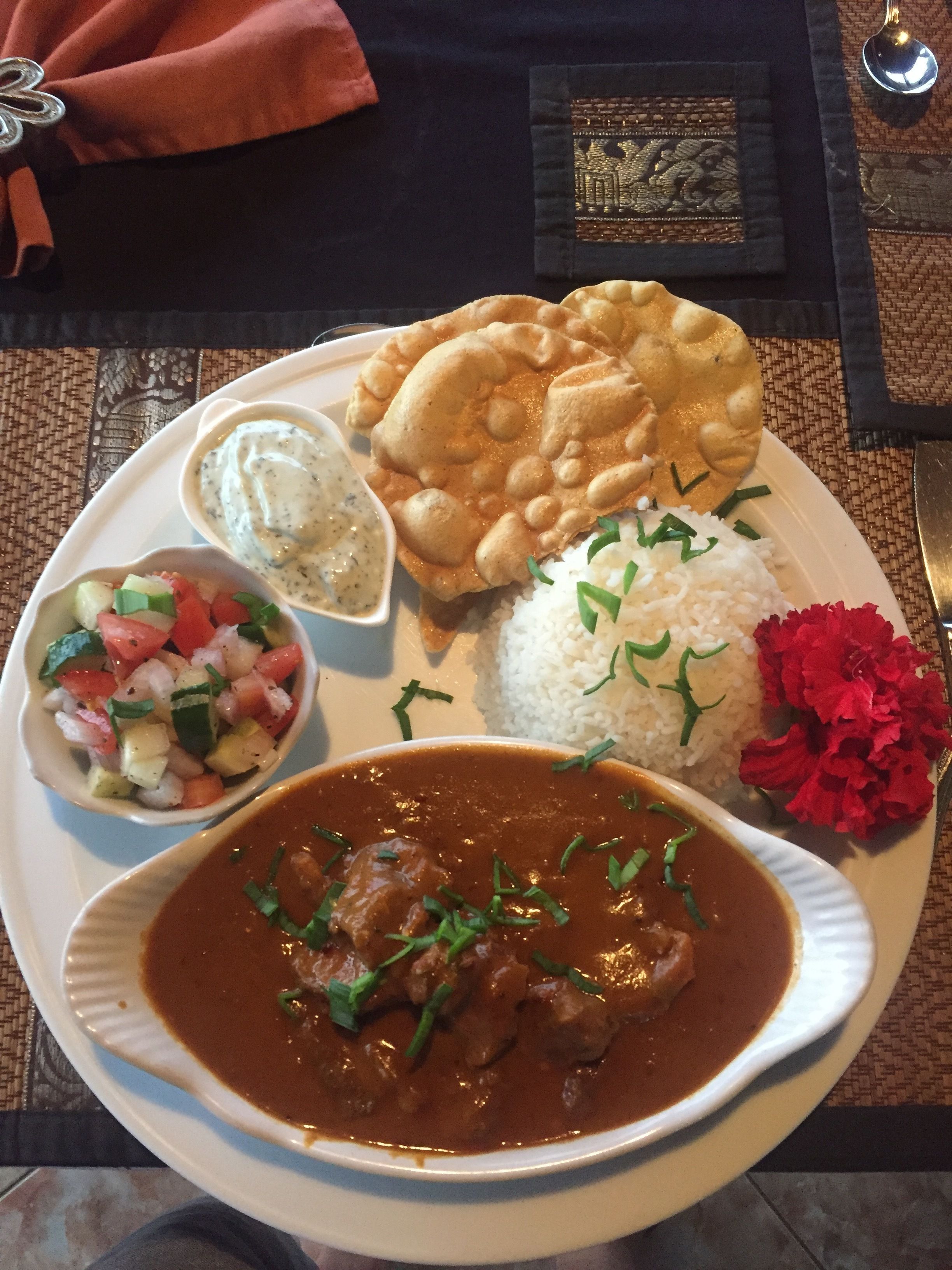 Une assiette de nourriture comprenant du riz, un plat en sauce, du pain plat et une salade en accompagnement.