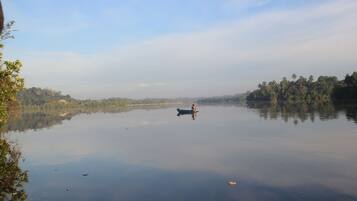 Un lago tranquilo con un bote en el centro, rodeado de árboles y un cielo despejado.