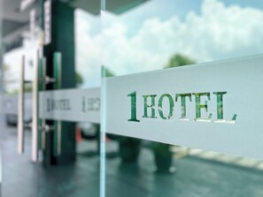 Une enseigne d’hôtel avec le nom « 1 HOTEL » écrit en lettres vertes sur un fond blanc.