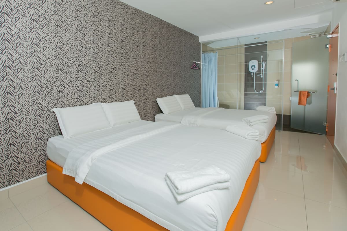 Une chambre d’hôtel avec deux lits, un espace douche et un mur décoré de motifs.