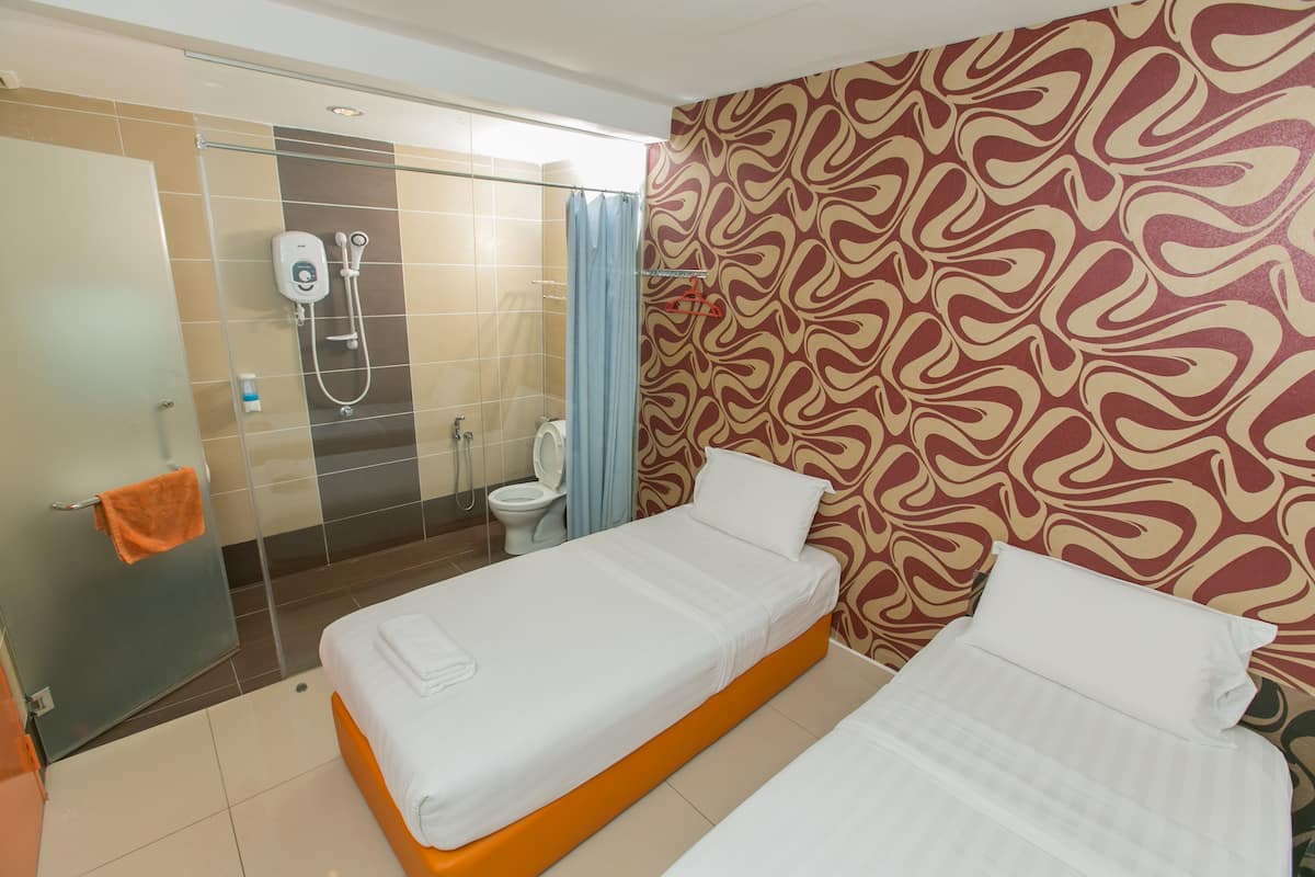 Une chambre d’hôtel avec deux lits, un espace douche et un mur décoré de motifs.
